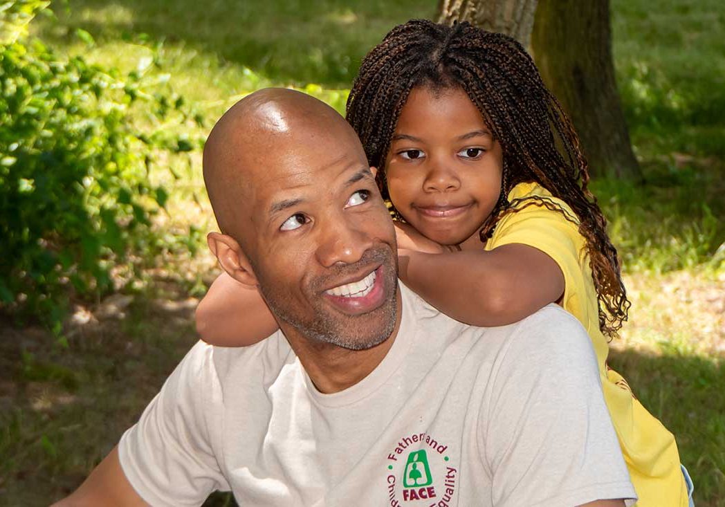 Black father with daughter hanging onto his back